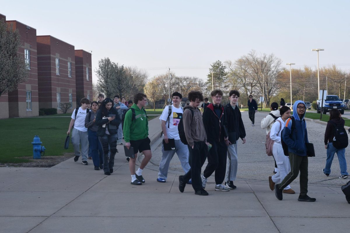 Two minutes before school begins, the lines to get in through the new metal detectors have students backed up to the bus lane.